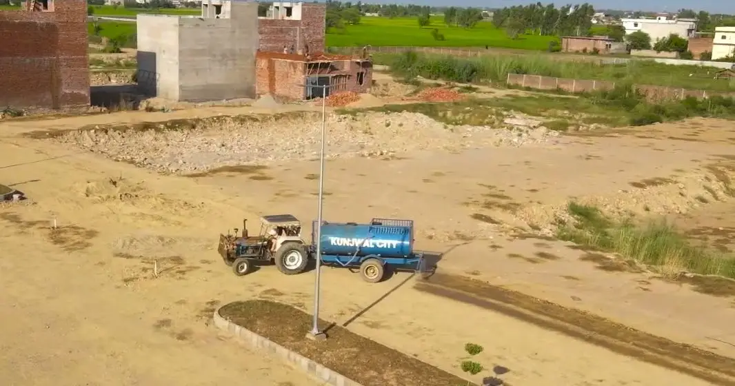 Houses under construction beside a new street-light pole, Kunjwal City, October 2026